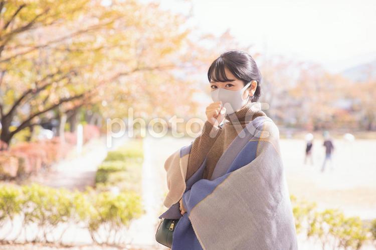 秋の公園でマスクをつけて咳き込む女性 マスク,コロナ,咳の写真素材