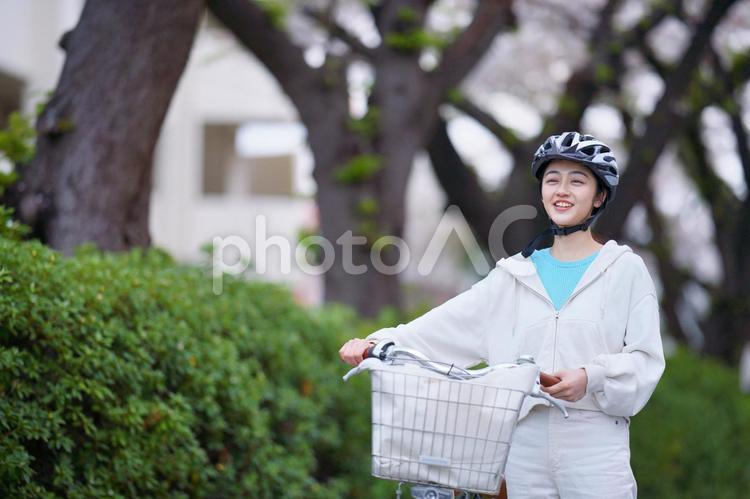 自転車を降りて誰かと話すヘルメットの女性 女性,大学生,春の写真素材