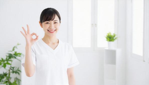笑顔でOKサインをする白衣の女性スタッフ 笑顔でOKサインをする白衣の女性スタッフの写真