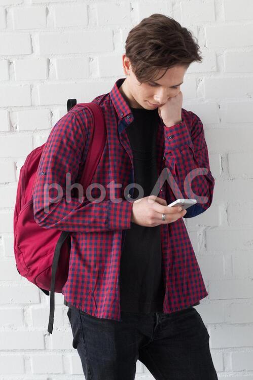 リュックサックを背負ってスマホを見ているティーンエイジャーの男の子3 ティーンズ,男子,外国人の写真素材
