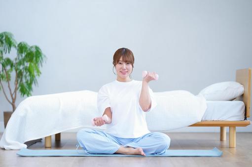 カメラ目線でダンベルで筋トレする女性 女性,ダンベル,持つの写真素材