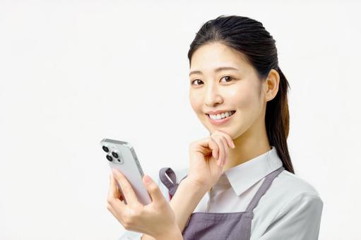 スマホを持ち考えるエプロンの女性 主婦 スマホを持ち考えるエプロンの女性 主婦 スマホ,女性,スマートフォンの写真素材