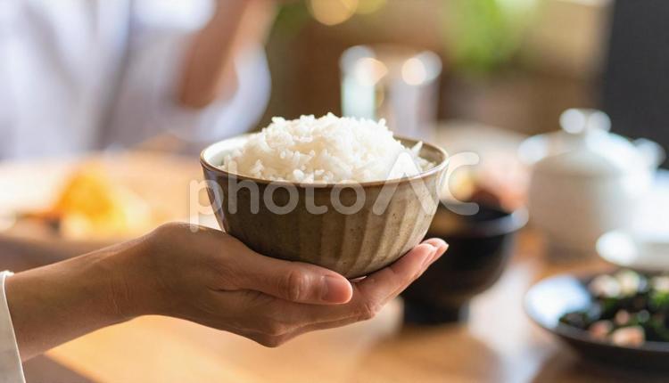 食卓を背景にお茶碗を持つ女性の手 ご飯,白ご飯,お茶碗の写真素材