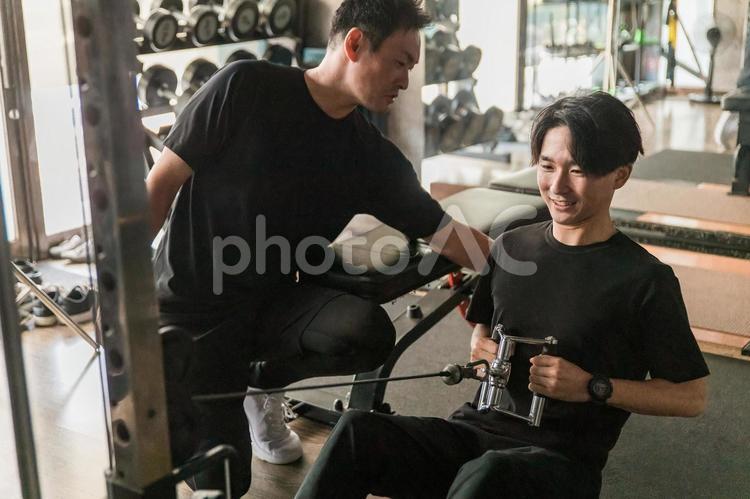 筋トレする男性とパーソナルトレーナー スポーツジム,筋トレ,ケーブルマシンの写真素材