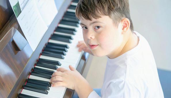 ピアノを弾くダウン症の少年 ピアノを弾くダウン症の少年の写真