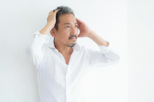 リビングでヘアケアをするミドルの男性 ヘアケア,育毛,ヘアセットの写真素材