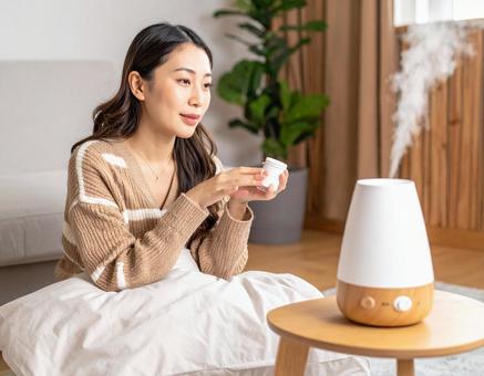 加湿器のそばでスキンケアをする女性の写真