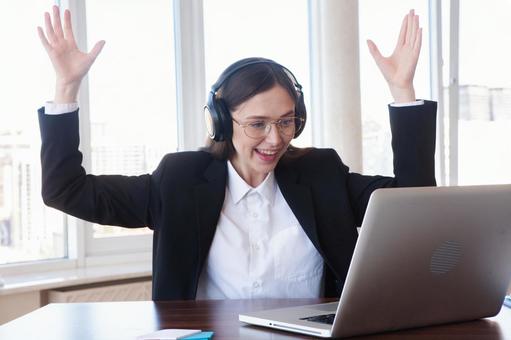 パソコンを見て両手をあげ喜ぶ女性 女性,外国人,ノートパソコンの写真素材