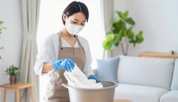 マスク、手袋、エプロン姿で手洗いする母親 マスク、手袋、エプロン姿で手洗いする母親の写真