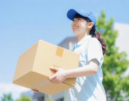 笑顔で荷物を運ぶ女性作業員 笑顔で荷物を運ぶ女性作業員の写真