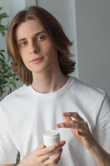 クリームを手に取るカメラ目線の男性の写真