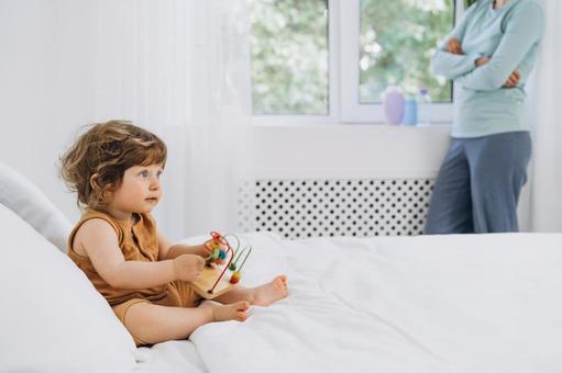 窓際で腕組みする人と玩具を持ち座る子供 窓際で腕組みする人と玩具を持ち座る子供 赤ちゃん,かわいい,玩具の写真素材