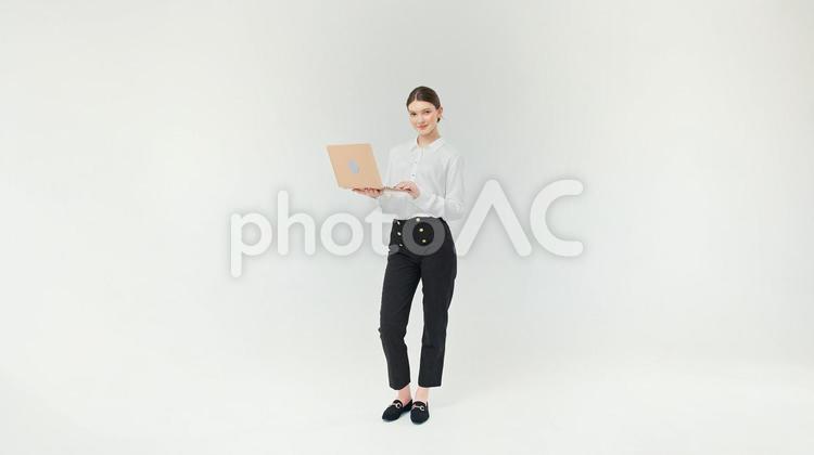 カメラ目線で微笑みパソコンを持っている女性 女性,微笑む,ノートパソコンの写真素材
