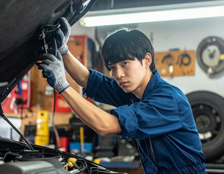 自動車工場でエンジン整備する男性スタッフ 自動車工場でエンジン整備する男性スタッフの写真