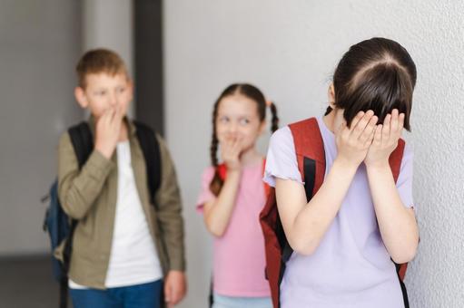 泣いている女の子と後ろで笑う生徒たち 男の子,女の子,子どもの写真素材