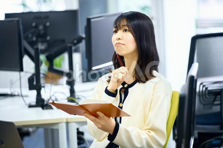 オフィスで手帳を使う女性　デスクワーク ビジネスウーマン,メモ帳,デスクワークの写真素材
