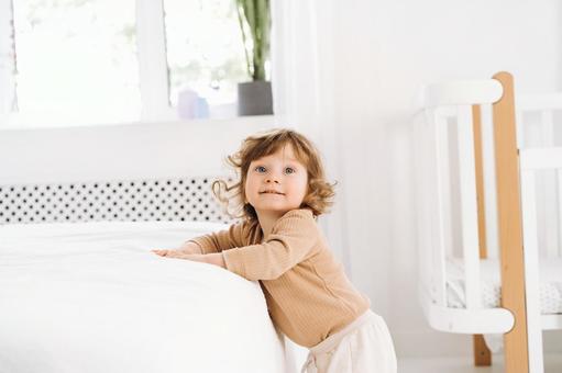 ベッドでつかまり立ちする子供 ベッドでつかまり立ちする子供の写真