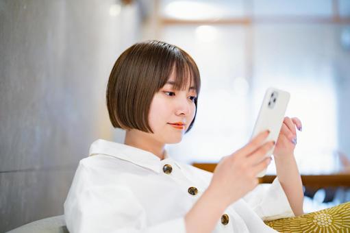 A woman operating a smartphone in the room, smartphone, smartphone, sns, JPG