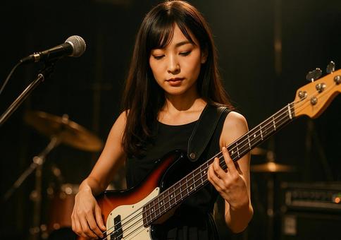 ライブでクールにベースを弾く真剣な女性の写真