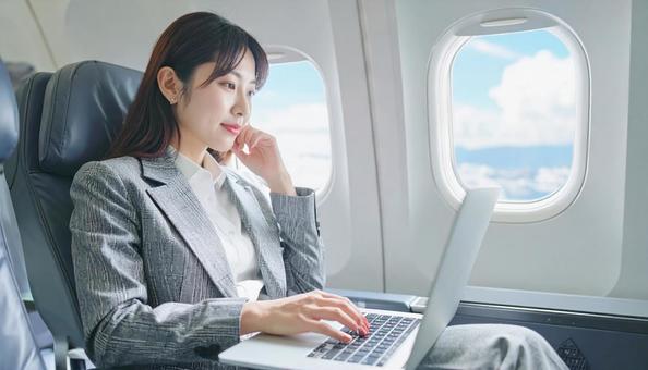 飛行機内で仕事をするビジネスマン 飛行機内で仕事をするビジネスマンの写真