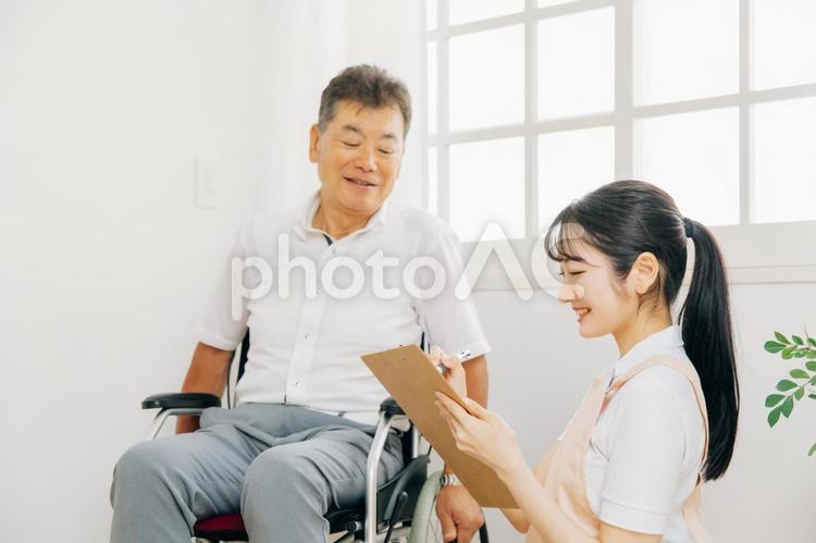 高齢者男性と話す介護士（メモ） ケアマネジャー,高齢者,介護士の写真素材