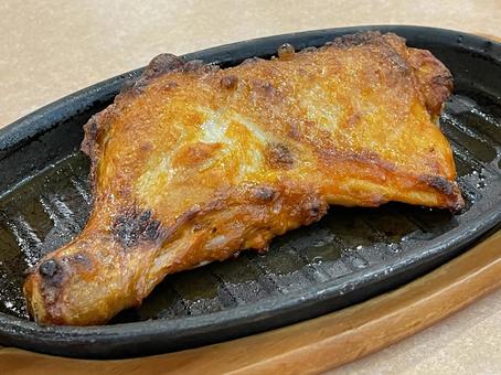 鉄板に乗った骨付きもも肉 鉄板に乗った骨付きもも肉の写真