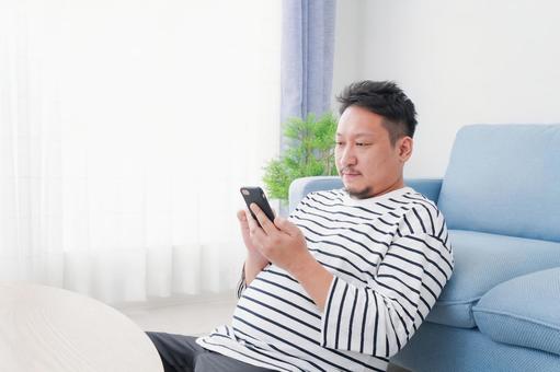 部屋でスマホを使う男性 ネット,写真,インターネットの写真素材