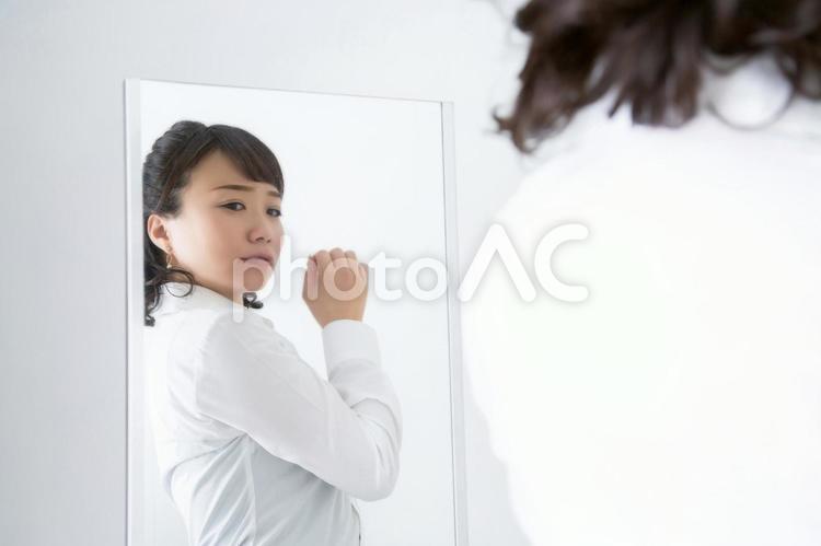鏡で体型をチェックする女性（困る） 体型,女性,困るの写真素材