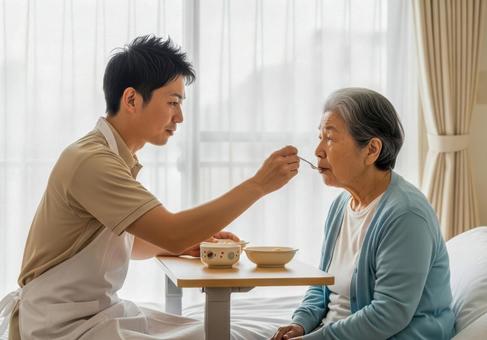 男性介護士が高齢女性に食事介助する場面 男性介護士が高齢女性に食事介助する場面の写真