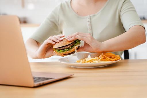 Hands of a person eating a hamburger while looking at a computer, on hand, female, people, JPG