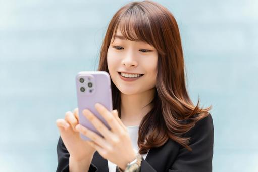 スマホを使う笑顔の女性・ビジネスウーマン 女性,スマホ,スマートフォンの写真素材