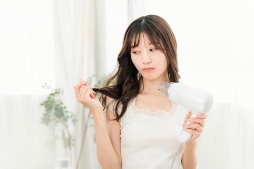 ヘアドライヤーで髪の毛を乾かす女性 ヘアドライヤーで髪の毛を乾かす女性 ドライヤー,ダメージヘア,傷むの写真素材