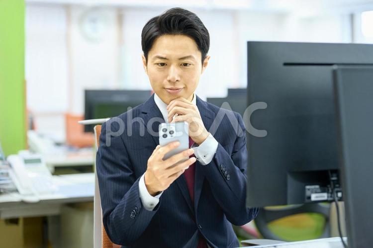 デスクワークするビジネスマン　スマホ ビジネスマン,デスクワーク,スマホの写真素材