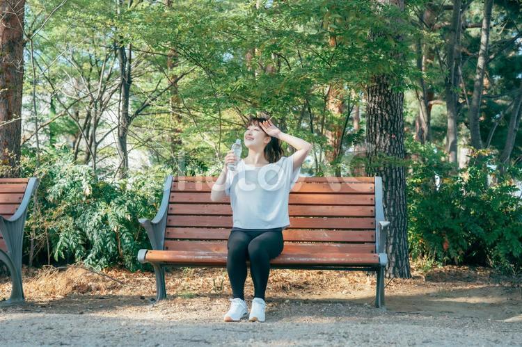 トレーニング中に休憩する女性（水を飲む・笑顔） 水分補給,汗,水の写真素材