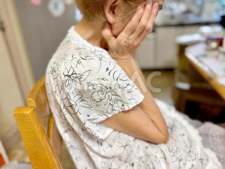 顔をおおいうなだれる半袖を着た高齢女性 高齢者,女性,人の写真素材