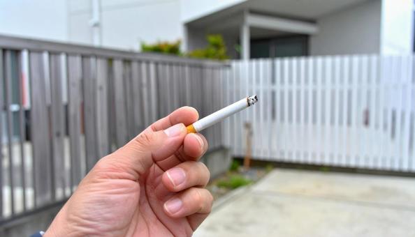 家の外でタバコを吸う日本人男性の手もと 家の外でタバコを吸う日本人男性の手もとの写真