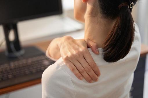 A business woman whose shoulders hurt when working from home, travailler à la maison, le télétravail, travail à distance, JPG