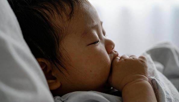 寝ながら指しゃぶりをする子供の横顔 寝ながら指しゃぶりをする子供の横顔の写真
