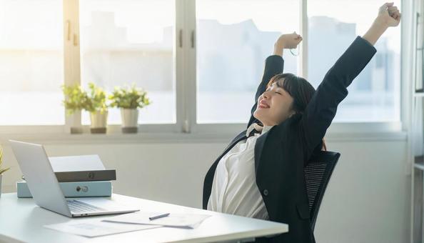仕事が終わり達成感で背伸びをする社員 仕事が終わり達成感で背伸びをする社員の写真