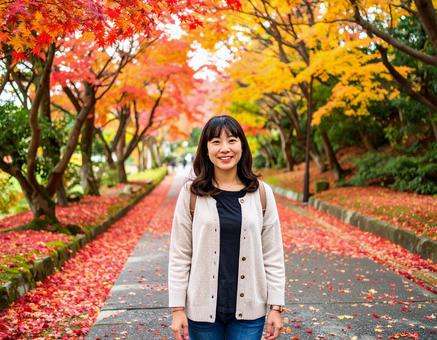 紅葉の道を散歩する女性 紅葉の道を散歩する女性の写真