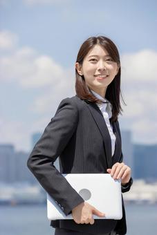 ノートパソコンを持ったビジネスウーマン ノートパソコンを持ったビジネスウーマン 女性,見上げる,ノートパソコンの写真素材
