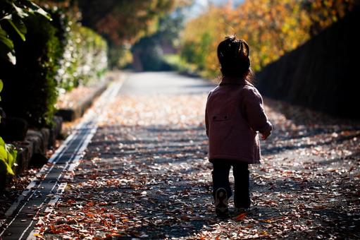 落ち葉の散る道路を歩く子供 落ち葉の散る道路を歩く子供 子供,シルエット,アスファルトの写真素材
