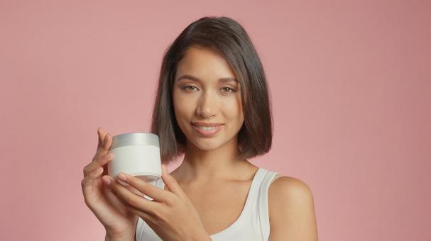 クリームジャーを見せて笑顔の女性 クリームジャーを見せて笑顔の女性 女性,外国人,アジア人の写真素材