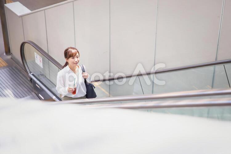 エスカレーターに乗る女性 エスカレーター,駅,通勤の写真素材