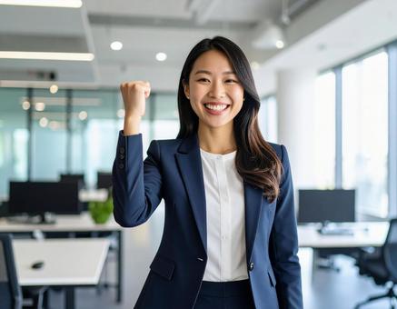 オフィスでガッツポーズする若い女性社員 オフィスでガッツポーズする若い女性社員の写真