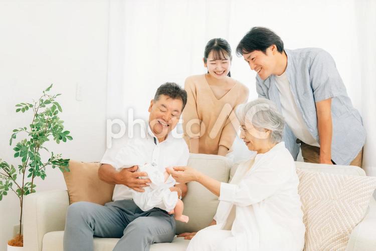 赤ちゃんを抱いた老夫婦と若い夫婦（里帰り） 孫,里帰り,帰省の写真素材