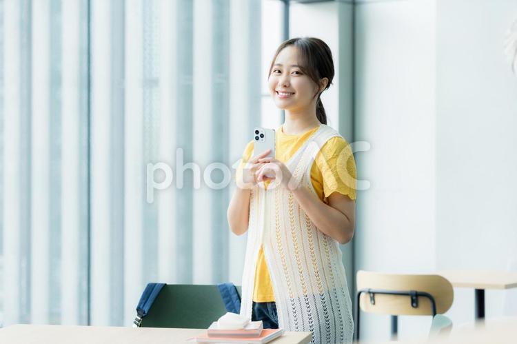 カフェでスマホを見る学生 スマホ,若い女性,笑顔の写真素材