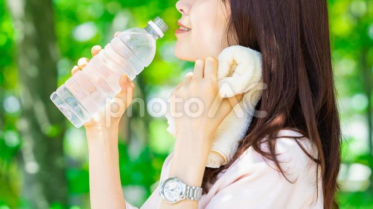 ペットボトルの水を飲む女性・熱中症対策 女性,笑顔,夏の写真素材