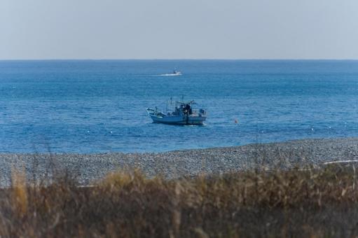 春の海に浮かぶ漁船と水平線 春の海に浮かぶ漁船と水平線の写真