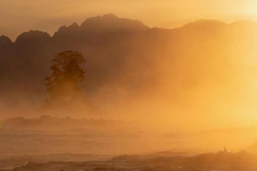 オレンジ色の毛嵐に霞む女岩 毛嵐,日の出,朝焼けの写真素材